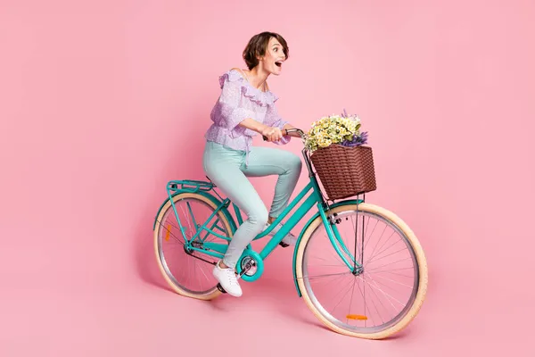 Foto lateral de perfil de tamanho completo de jovens atraentes felizes animado louco menina andar de bicicleta rápido isolado no fundo cor-de-rosa — Fotografia de Stock