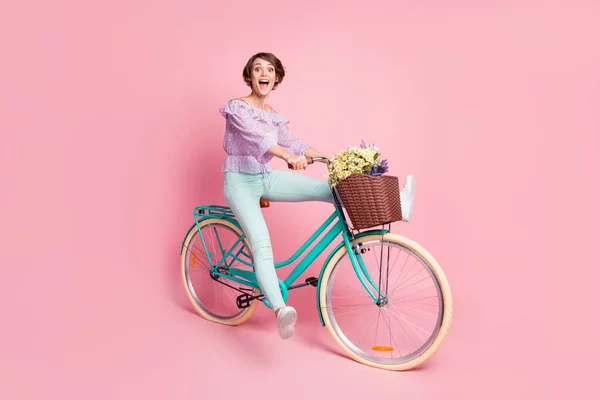 Volledige lengte foto portret van opgewonden meisje paardrijden fiets geïsoleerd op pastel roze gekleurde achtergrond — Stockfoto