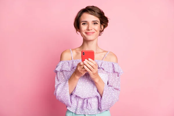 Фото молодой красивой счастливой веселой позитивной девушки с помощью телефона просматривать в социальной сети изолированы на розовом фоне цвета — стоковое фото