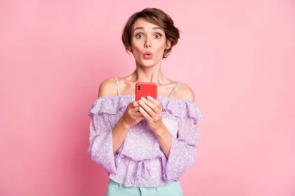 Foto retrato de mulher chocada segurando telefone em duas mãos isoladas no fundo de cor rosa pastel — Fotografia de Stock