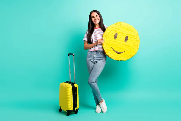 Full size photo of nice brunette optimistic long hairdo lady hold pinata bag wear t-shirt jeans sneakers isolated on teal color background — Stock Photo, Image