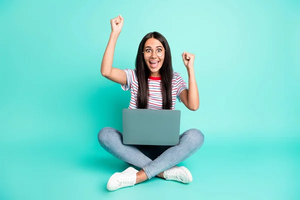 Full size photo of nice hooray lady work laptop sit hands fists wear spectacles t-shirt jeans sneakers isolated on teal background — Stock Photo, Image