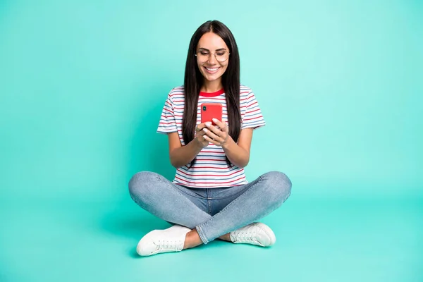 Портрет повного тіла чарівної позитивної леді сидить подивитися телефон, друкуючи зубну посмішку ізольовано на бірюзовому кольоровому фоні — стокове фото