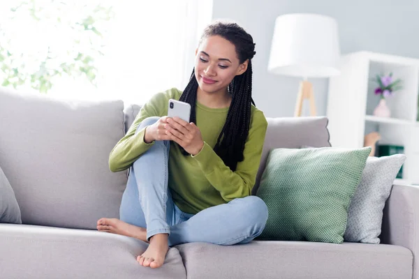 Foto de encantadora bonita mujer vestida suéter sentado sofá charlando dispositivo moderno sonriendo en el interior de la casa habitación en casa — Foto de Stock