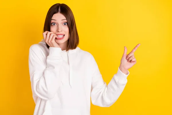 Photo of excited lady bite fingernails indicate finger empty space wear white hoodie isolated yellow color background — Stock Photo, Image