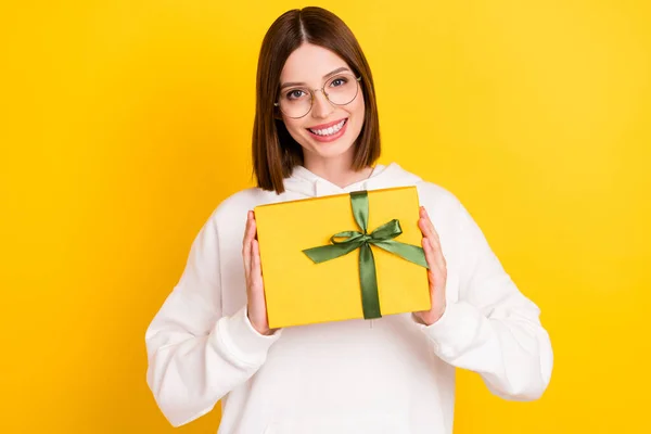 Foto de alegre dama positiva celebrar decorado giftbox desgaste especificaciones sudadera con capucha blanca aislado color amarillo fondo —  Fotos de Stock