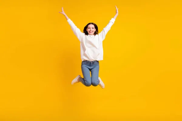 Foto di funky allegra signora salto alzare le mani indossare bianco felpa con cappuccio jeans calzature isolato colore giallo sfondo — Foto Stock