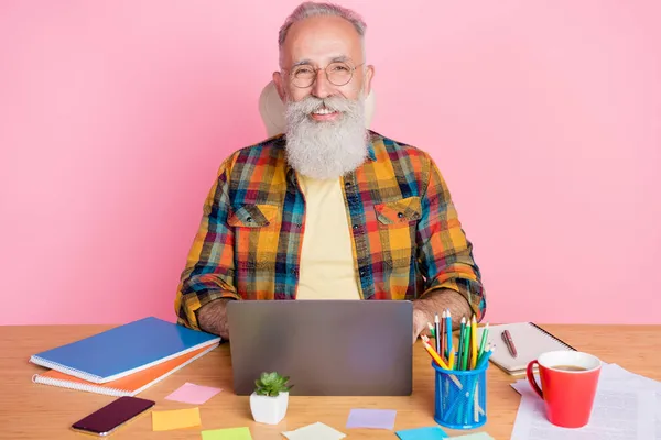 Portrait d'homme joyeux et intelligent aux cheveux gris apprenant des cours en ligne qu'il projette isolé sur fond rose pastel — Photo