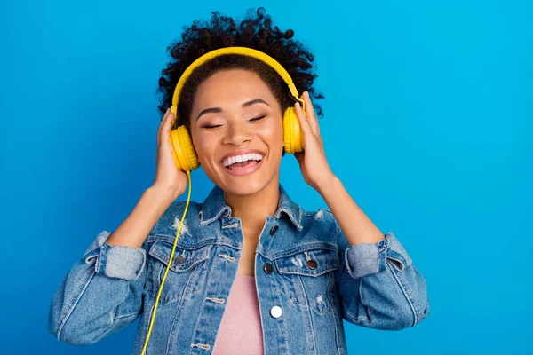Φωτογραφία από δροσερό ευτυχισμένη νεαρή γυναίκα φορούν ακουστικά απολαμβάνουν μουσική που απομονώνονται σε μπλε φόντο χρώμα — Φωτογραφία Αρχείου