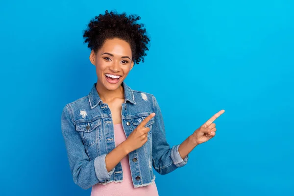 Foto van jonge vrolijke afro-Amerikaanse vrouw wijzen vinger lege ruimte nieuws verbaasd geïsoleerd op blauwe kleur achtergrond — Stockfoto