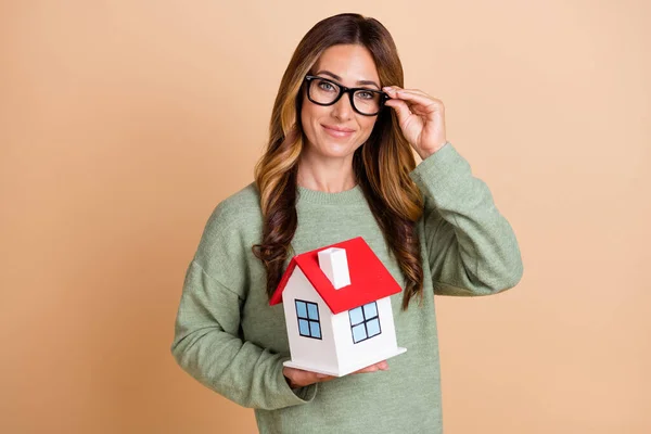 Fényképezés portré női ügynök visel szemüveg mosolygós tartás kis ház új elszigetelt pasztell bézs szín háttér — Stock Fotó