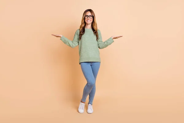 Vista completa del tamaño del cuerpo de la atractiva mujer de pelo ondulado alegre sosteniendo espacio de copia aislado sobre fondo de color pastel beige —  Fotos de Stock