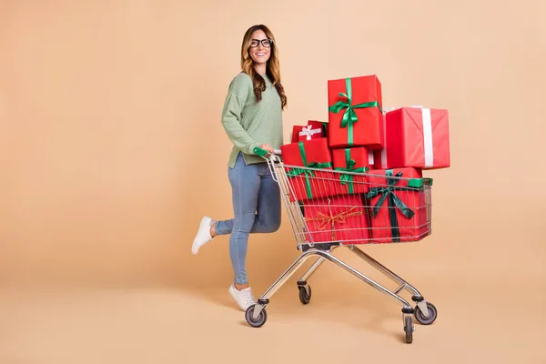 Tam boy vücut ölçülerinde bir kadın alışveriş merkezinde elinde og hediyelerle yürüyor izole edilmiş pastel bej rengi arka planda — Stok fotoğraf