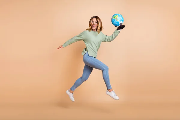 Comprimento total tamanho do corpo foto mulher saltando alta corrida mantendo globo isolado pastel cor bege fundo — Fotografia de Stock