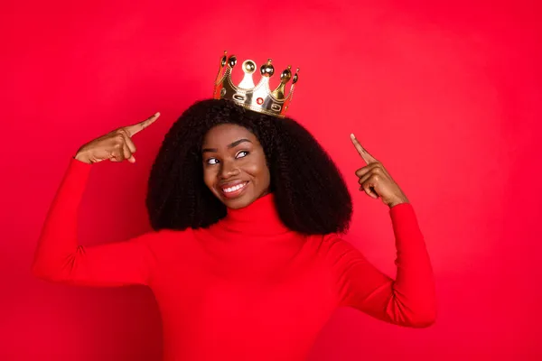 Photo of young african woman happy positive smile indicate fingers golden crown royalty proud isolated over red color background — Stock Photo, Image