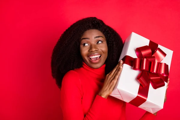 Фото молодой взволнованной черной женщины счастливой позитивной улыбкой получить подарок коробку день рождения встряхнуть изолированы на красный цвет фона — стоковое фото