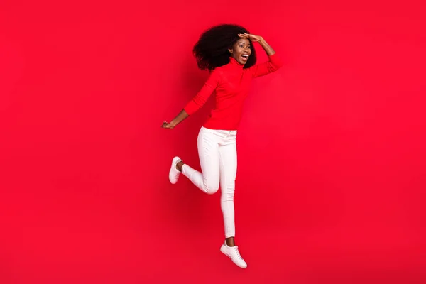 Genç Afrikalı mutlu bir kadının tam boy profil fotoğrafı. Yukarı zıpla. Kırmızı arka planda soyutlanmış bir şekilde ileriye bak. — Stok fotoğraf
