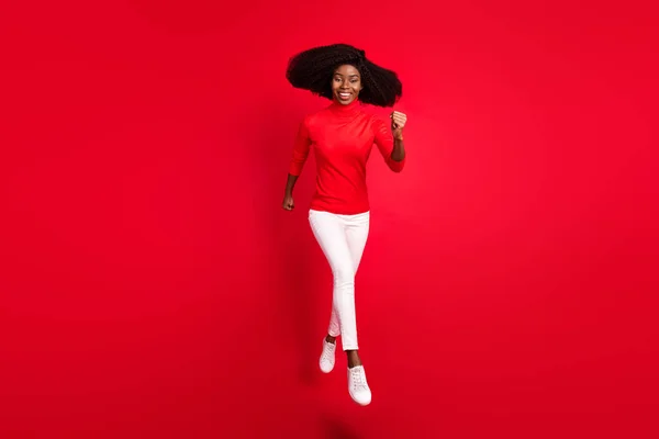 Full tělo fotografie mladé africké ženy šťastný pozitivní úsměv vyskočit jít chůze běh izolované přes červené barvy pozadí — Stock fotografie