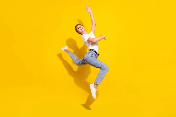 Foto lateral de perfil de longitud completa de niña feliz sonrisa positiva gimnasia salto deportivo aislado sobre fondo de color amarillo —  Fotos de Stock