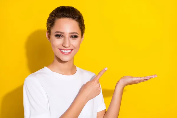 Fénykép a fiatal vonzó lány boldog pozitív mosoly pont ujj promo termék ajánlat hirdetés elszigetelt sárga szín háttér — Stock Fotó