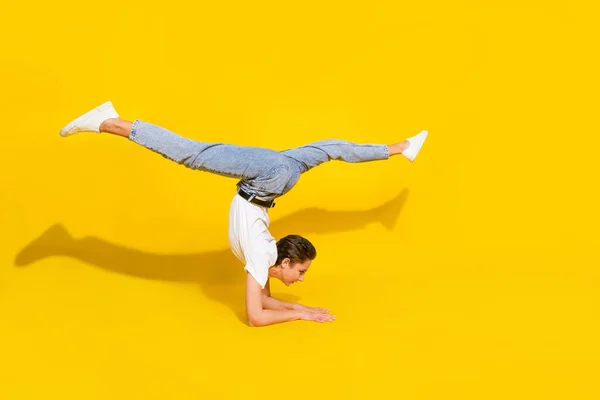 Foto lateral de perfil de cuerpo completo de la joven pie en las manos estiramiento acrobat flexible dividido aislado sobre fondo de color amarillo —  Fotos de Stock