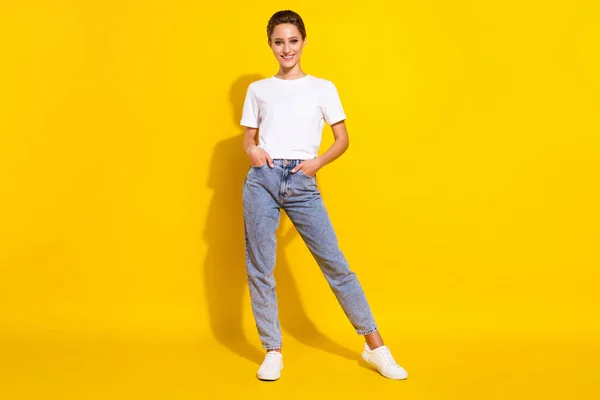 Foto em tamanho completo de bonito penteado marrom jovem senhora stand desgaste branco t-shirt jeans isolado no fundo de cor amarela — Fotografia de Stock