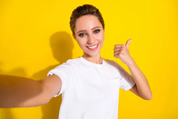 Foto di sognante carino giovane signora indossare abiti casual mostrando pollice su prendendo selfie sorridente isolato colore giallo sfondo — Foto Stock