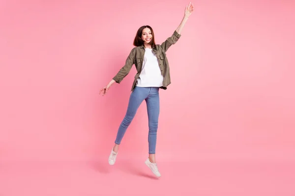 Full storlek foto av söt kort frisyr dam hoppa bära khaki skjorta jeans sneakers isolerade på rosa färg bakgrund — Stockfoto