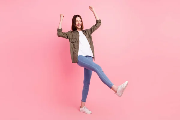 Full size photo of impressed brunette hairdo lady hands fists yell wear green shirt jeans isolated on pink color background — Stock Photo, Image