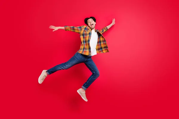 Foto von lustigen charmanten jungen Herrn tragen kariertes Outfit lächelnd springen hoch fliegen isoliert rote Farbe Hintergrund — Stockfoto
