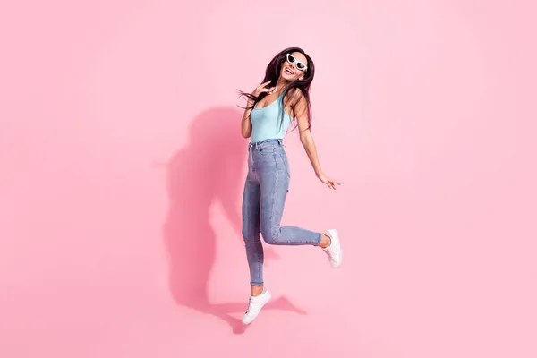 Full length body size photo of smiling woman wearing sunglass jumping up happy isolated on pastel pink color background — Stock Photo, Image