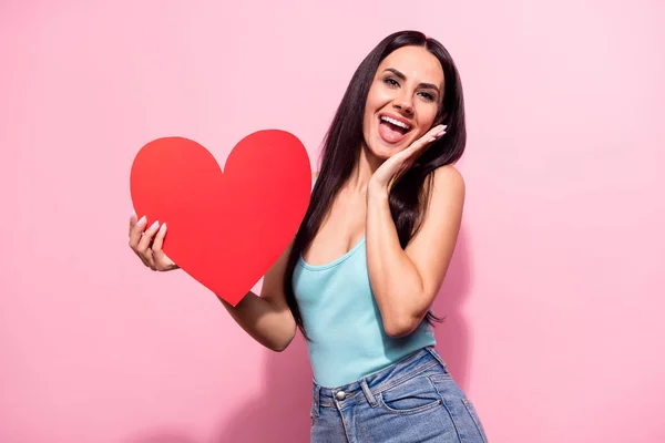 Portrait of attractive impressed girlish cheerful girl holding big heart having fun news isolated over pink pastel color background — Stock Photo, Image