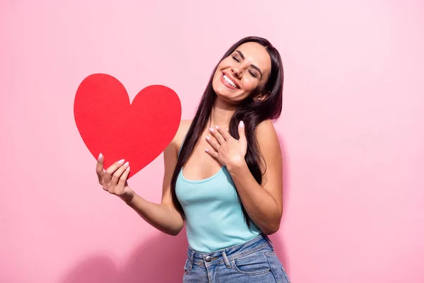 Portret van aantrekkelijke onder de indruk dromerig vrolijk meisje houden hart vorm poseren geïsoleerd over roze pastel kleur achtergrond — Stockfoto