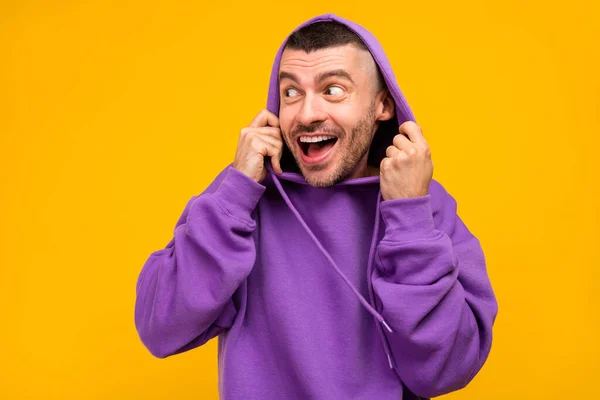 Photo d'impressionné millennial brunet guy look porter capuche violette isolé sur fond de couleur jaune — Photo