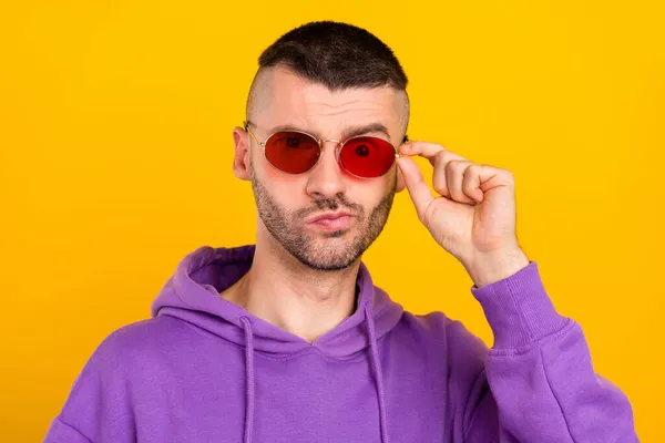 Foto de chico moreno joven inseguro usar gafas sudadera con capucha púrpura aislado sobre fondo de color amarillo — Foto de Stock