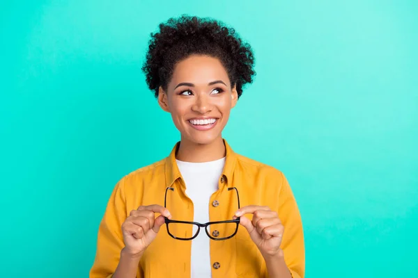 Foto di giovane ragazza nera tenere occhiali oculista sguardo spazio vuoto isolato su sfondo di colore turchese — Foto Stock