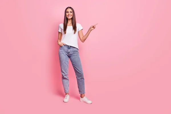 Foto de longitud completa de cool millennial morena lady point wear camiseta jeans zapatillas aisladas sobre fondo rosa —  Fotos de Stock