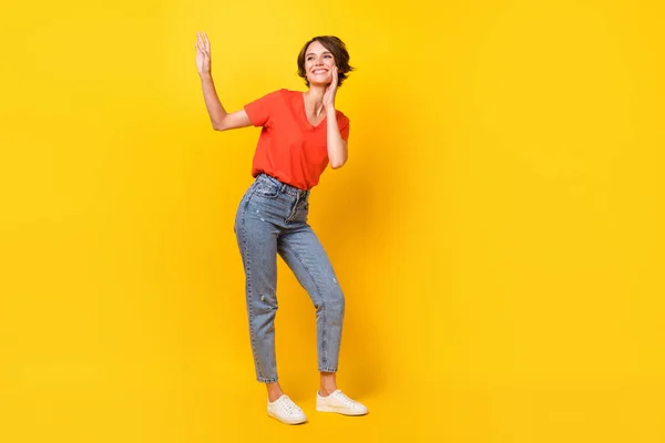 Foto de tamaño completo de la fresca morena optimista dama danza desgaste rojo camiseta jeans zapatillas aisladas sobre fondo de color amarillo vivo —  Fotos de Stock