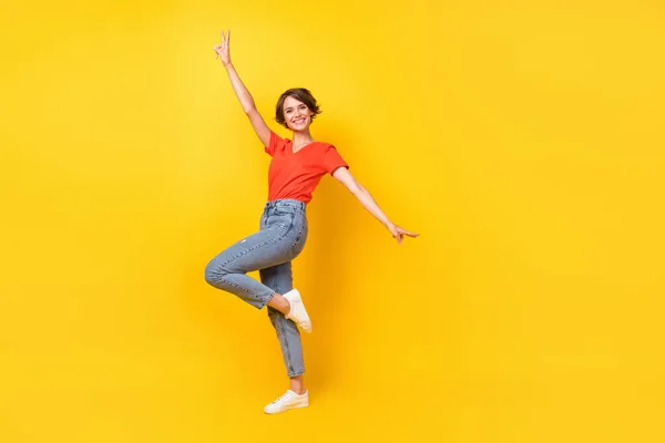 Foto de perfil de tamaño completo de cool morena mujer optimista danza desgaste rojo camiseta jeans zapatillas aisladas sobre fondo de color amarillo —  Fotos de Stock