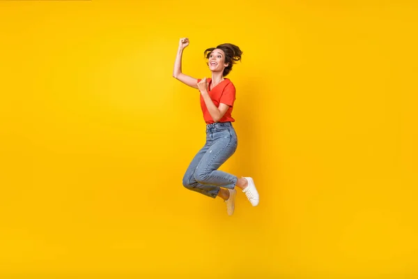 フルサイズプロフィール写真のhoorayブルネット短い髪型女性ジャンプ着用tシャツジーンズスニーカー隔離された黄色の色の背景 — ストック写真