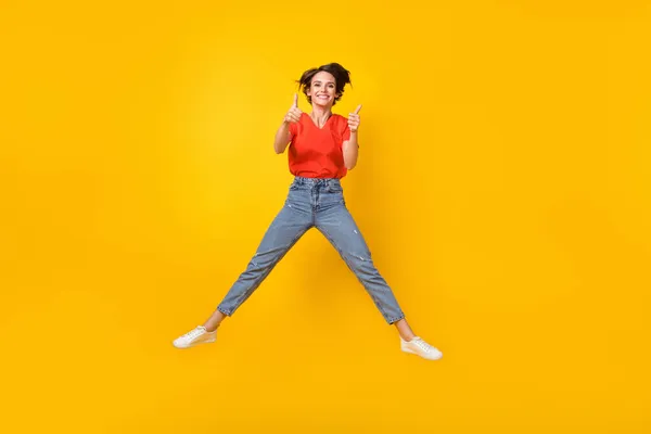 Foto de tamaño completo de la morena optimista peinado corto lady jump show ok signo desgaste camiseta jeans zapatillas aisladas sobre fondo amarillo —  Fotos de Stock
