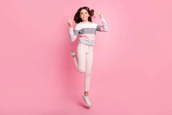 Foto de longitud completa de niña atractiva saltar hasta mostrar v-signos de viaje disfrutar aislado en el fondo de color rosa — Foto de Stock