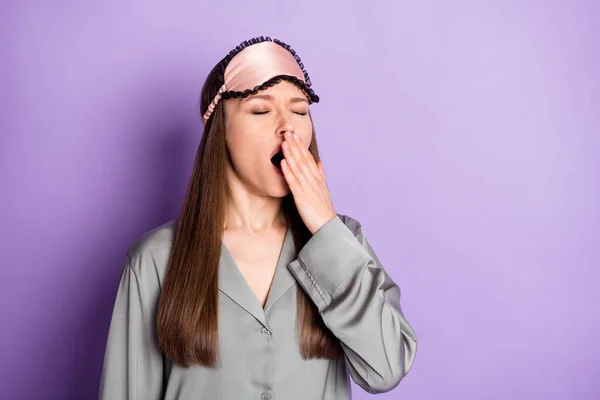 Portrait d'une jolie fille fatiguée et épuisée portant un pyjama se réveillant bâillant isolé sur fond violet couleur pourpre — Photo