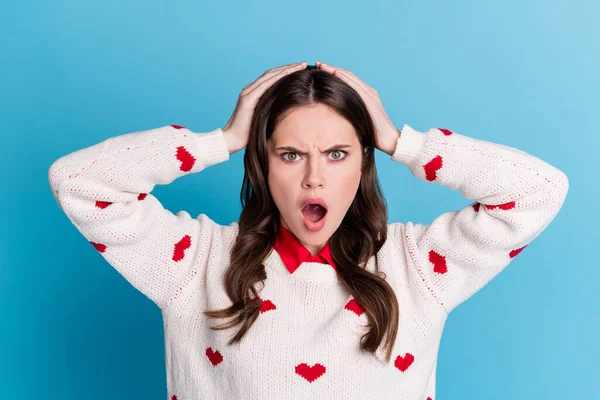 Foto de emocionada mujer joven conmocionada vestidos corazones impresión pulóver brazos cabeza ojos grandes aislados color azul fondo —  Fotos de Stock