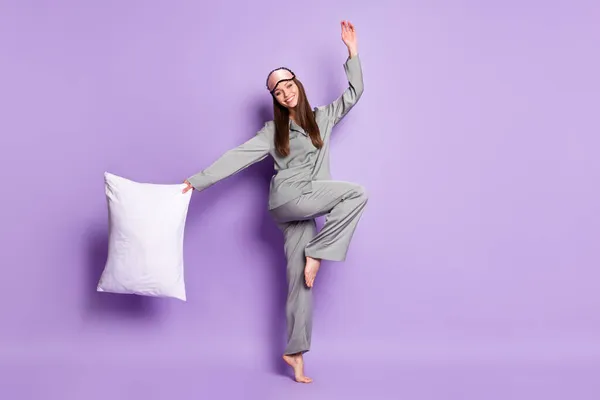 Volledige lengte lichaamsgrootte uitzicht van mooie vrolijke meisje dragen pyjama dragen kussen springen plezier geïsoleerd op violet paarse kleur achtergrond — Stockfoto