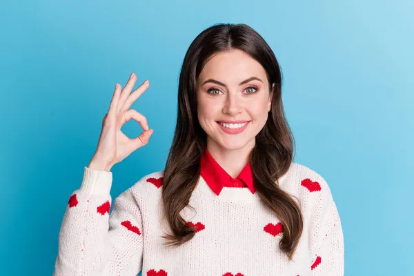 Foto de adorable dulce mujer joven vestidos corazones impresión pullover mostrando signo okey aislado fondo de color azul —  Fotos de Stock