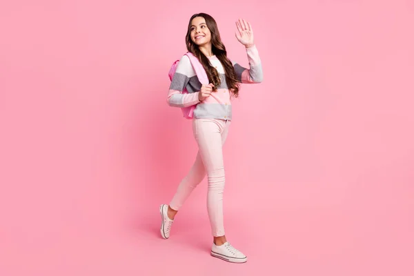 Foto de tamaño completo de la joven alegre alegre colegiala sonriente ir a caminar con mochila decir hola aislado en el fondo de color rosa —  Fotos de Stock