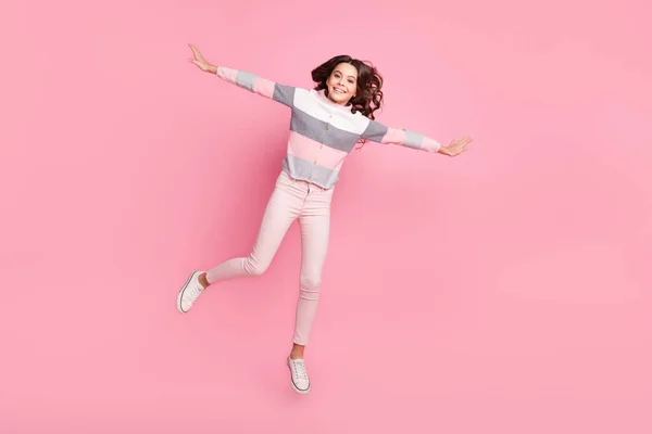 Foto de cuerpo completo de atractiva chica joven enérgica saltar aire hacer alas manos aisladas sobre fondo de color rosa —  Fotos de Stock