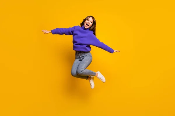 Photo of funny pretty young woman wear purple pullover jumping high arms hands sides isolated yellow color background — Stock Photo, Image