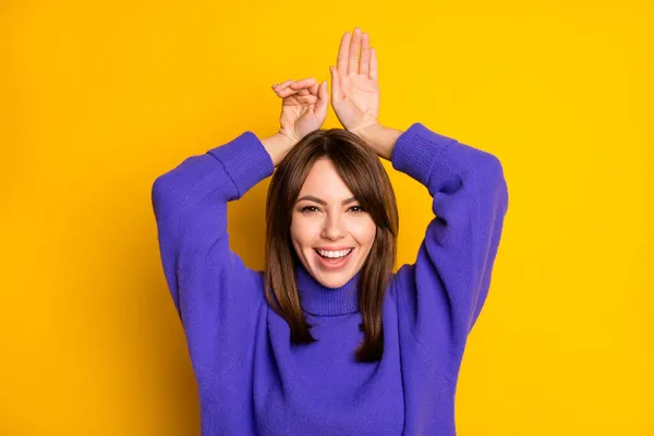 Fénykép a fiatal boldog jókedv mosolygós lány mutatja nyuszi fülek viselni lila pulóver elszigetelt sárga színű háttér — Stock Fotó
